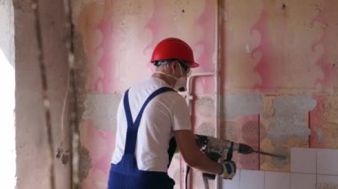 Müteahhit duvara bakan seramik fayansları kaldırır. İşçi sökme ve yıkma işlerini döner çekiç matkabıyla yapıyor. Daire tadilatı işe yarıyor. Üniformalı ve çalışkan bir mimar..