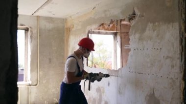 Adam elle sökme ve yıkım işleriyle uğraşıyor. Dairenin tadilatı için büyük çekiçle vuruyor. Müteahhit balyozla duvarı yıkar ve yeniden düzenleme için delik açar. Üniformalı inşaat işçisi.