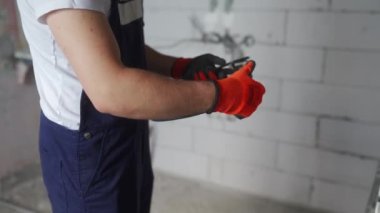 Elektrikçi kabloları döşeyip, eve elektrik kabloları yerleştiriyor. Tulum ve eldiven giyen inşaatçı inşaat alanına elektrik kabloları yerleştiriyor. Adam apartman tadilatı yapıyor..