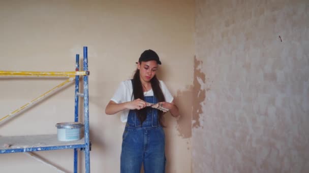 专业的灰泥匠女性会在墙壁上吐痰 涂上石膏 涂上工作服和球帽 年轻的女石膏墙壁 在建筑工地做装修工作 — 图库视频影像