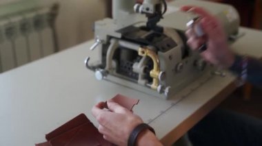 Deri ustası atölyesinde çalışıyor. Usta deri ürünler yapıyor. Elektrikli deri kayak seyreltme makinesi ya da sanayi düz kürek deri kesicisiyle çalışan adam, kalınlığı ölçer..