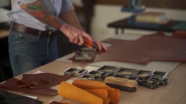 皮革工匠在一个车间工作 主要生产皮革制品 人切皮革板形用于模压冲切皮革冲切刀 工艺切割模子上的男装 — 图库视频影像