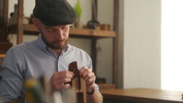 革職人は工房で働く 革の財布を作るマスター 男は革細工のための合板ステッチポニーや木製の視覚を使用しています 男とともにA針と糸縫製商品でAtelier — ストック動画