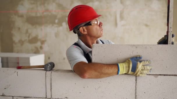 벽돌공이나 벽돌공 은자가 공기층 콘크리트 블록으로 벽돌을 쌓는다 업자들은 레이저 — 비디오