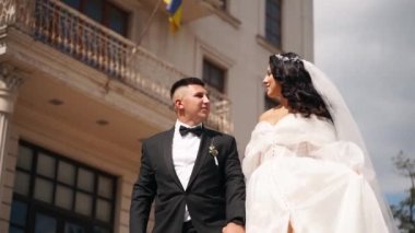 Gelin ve damat lüks malikane avlusunda mermer merdivenlerden iniyorlar. Beyaz elbiseli bir adam ve kadın, saray bahçesinde el ele tutuşarak uzun bir peçe yürüyüşü. Yeni evliler bir düğün mekanında seremoniye giderler..