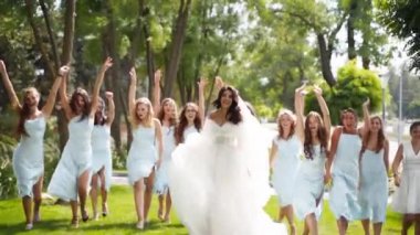 Güzel gelin, soluk mavi elbiseli güzel nedimeler parkta koşup el sallıyorlar. Uzun soluk duvağı olan, zarif, kanat çırpan beyaz elbiseli bir kadın arkadaşlarıyla parti yapıyor. Yavaş çekim.