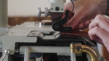 Deri ustası atölyesinde çalışıyor. Usta deri ürünler yapıyor. Elektrikli deri kayak seyreltme makinesi ya da sanayi düz kürek deri kesicisiyle çalışan adam, kalınlığı ölçer..