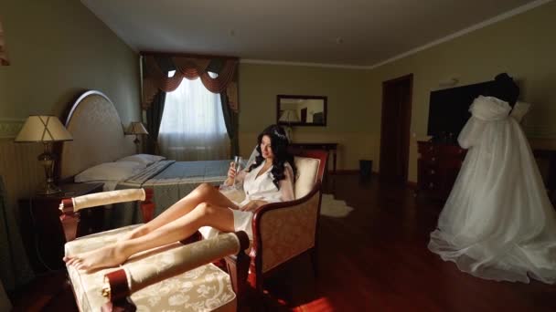 Csinos Menyasszony Fehérneműben Selyemköntösben Pezsgőt Iszik Karosszéken Ülve Szobájában Figyelmes — Stock videók