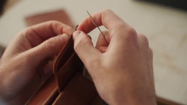 革職人は工房で働く 革の財布を作るマスター 男は革細工のための合板ステッチポニーや木製の視覚を使用しています 男とともにA針と糸縫製商品でAtelier — ストック動画