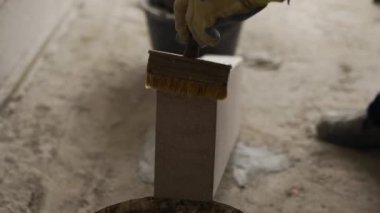 Tuğla ustası, otoklava kaplı beton bloklara çentikli mala ve spatula ile yapıştırıcı sürüyor. Tuğla işçiliği müteahhidi, inşaat alanında inşaat yaparken köpük betona havan topu koydu..