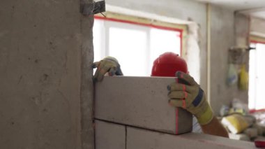 Müteahhit, beton duvara tabancayla poliüretan köpük yapıştırıcı sürerek otomatik kaplamalı beton tuğlayı yapıştırıyor. İşçi PU köpüğü püskürtür. İzole görünüm.