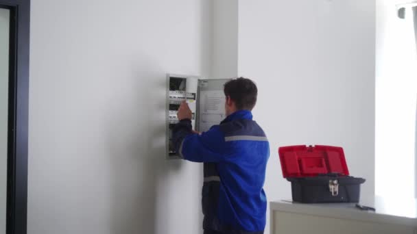 电工拆开一个电保险丝盒 穿制服的主人放下电板来固定电力 维修人员通过检查断路器和开关来解决家庭问题 — 图库视频影像
