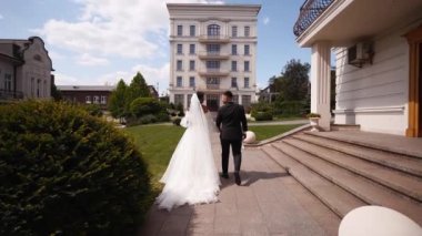 Gelin ve damat lüks malikanenin avlusunda kaldırım boyunca yürüyorlar. Beyaz elbiseli adam ve kadın saray bahçesinde el ele tutuşarak yürüyor. Yeni evliler bir düğün mekanında seremoniye giderler..