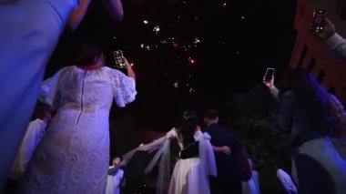 Damat ve gelin gökyüzünde havai fişekleri izliyor. Düğün gününün sonunda aşık bir çift öpüşür. Heyecanlı konuklar ateşe bakıyor..