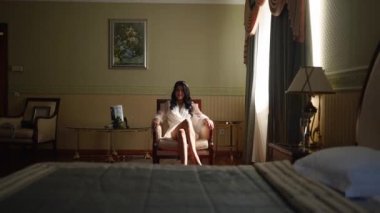 Çekici kadının bacak bacak üstüne atması baştan çıkarıcı bir şekilde koltukta oturması. İç çamaşırlı ve beyaz ipekli gelin filmdeki gibi bacak bacak üstüne atıyor..