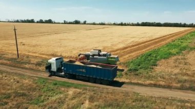 2021-07-08 Ukrayna, Nikolske. Hasatlardan gelen tahılları tarladaki tahıl kamyonuna yüklüyorlar. Hasat boşaltan hasatçı, hasat edilen buğdayı kamyonun gövdesine boşaltıyor. Hasat mevsimi. Hava aracı görünümü.