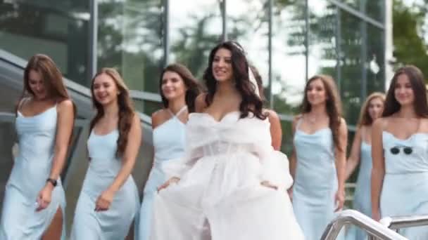 漂亮的新娘 穿着浅蓝色衣服的漂亮的伴娘 手舞足蹈地走着 穿着优雅飘逸的白色婚纱的女人 与女朋友们一起在派对上嬉戏 慢动作 — 图库视频影像