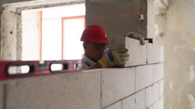 Tuğlacı ya da duvar ustası otoklastlı beton bloklardan duvar inşa etmek için tuğla döşüyorlar. Tuğla işçiliği müteahhidi lazer seviyesinde inşaat yapan köpük betonla blok çalışması yapıyor..