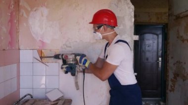 Müteahhit duvara bakan seramik fayansları kaldırır. İşçi sökme ve yıkma işlerini döner çekiç matkabıyla yapıyor. Daire tadilatı işe yarıyor. Üniformalı ve çalışkan bir mimar..