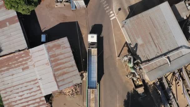穀物エレベーターサイロの工業地帯を通って運転する穀物のローリーまたはダンプトラックの上からの空中ビュー 道路に沿って運転空のボディトレーラーのトップビュー エアドローンのカメラ映像 — ストック動画