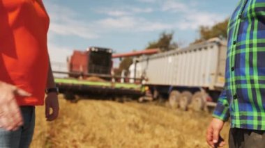 Çiftçi ve tarım uzmanı buğday tarlalarında el sıkışıyor. Tarım işi sözleşmesi konsepti. Hasat sürücüsü ve çiftlik sahibi hasat mevsiminde pazarlık yapıyorlar. Tokalaşma