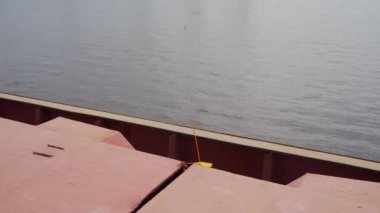 Seafarer tears off protective lead seal from cargo holds with on bulker ship at sea terminal in seaport. Shipping agent removes container door lock for transportation on a vessel arrival.