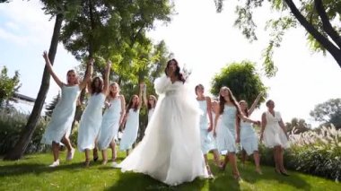 Güzel gelin ve soluk mavi elbiseli güzel nedimeleri parkta el sallayarak yürüyorlar. Uzun, havalı duvağı olan bir kadın zarif bir beyaz elbise partisinde arkadaşlarıyla kucaklaşır. Yavaş çekim.