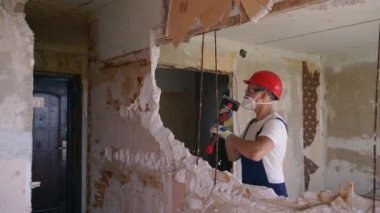 Adam elle sökme ve yıkım işleriyle uğraşıyor. Dairenin tadilatı için büyük çekiçle vuruyor. Müteahhit balyozla duvarı yıkar ve yeniden düzenleme için delik açar. Üniformalı inşaat işçisi.