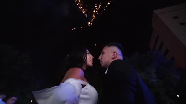 新郎和新娘在空中观看烟火 在结婚当天结束时 恋人在恋爱中亲吻 兴奋的客人看着火堆 — 图库视频影像