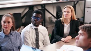 Businessman reporting to multiethnic partners audience in conference room. Diverse international team listen to CEO on meeting in office. Corporate people discuss business strategy on briefing.