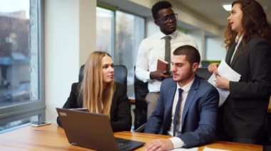 Diverse office corporate workers discuss project on laptop display in office. Multiethnic people planning startup strategy on meeting. Business team consulting on product design on a creative brief.