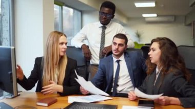 Business woman shows data, design for multiethnic coworkers on PC. International business partners discuss project on meeting in office. Diverse corporate team planning startup. People brainstorming.