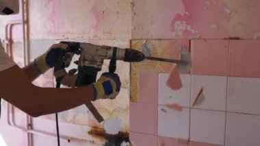 Müteahhit duvara bakan seramik fayansları kaldırır. İşçi sökme ve yıkma işlerini döner çekiç matkabıyla yapıyor. Daire tadilatı işe yarıyor. Üniformalı ve çalışkan bir mimar..