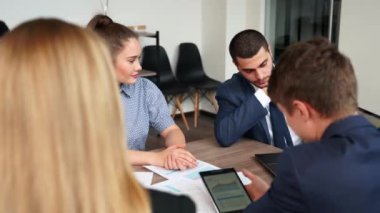 Businessman shows presentation with charts, diagrams on laptop for multiethnic partners. Startup team discuss project results. Diverse multinational people listening ceo on board meeting in an office.