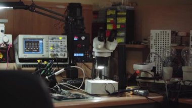 Electronics repair service workshop with soldering and diagnostics equopment. Oscilloscope, microscope and soldering iron on a workspace table.