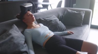 Woman in virtual reality googles enters metaverse immersive expirience via headset interface resting on sofa in minimalistic interior. Girl gaming in a cyber space. Futuristic concept.