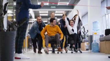 Neşeli insanlar iş molasında eğlenirler. İki takım ofis koridorunda tekerlekli sandalyede yarışıyor. Meslektaşlar iş arkadaşlarını sandalyeye oturtuyor. Kazananlar sevinir. Çalışanlar akıllı telefonlardan film çekiyor..