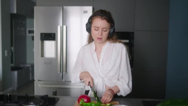Woman Headphones Making Salad Vegetables Has Fun Dancing Modern Kitchen — Vídeo de Stock