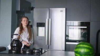 Economical inflation. Woman in kitchen looking at cash receipt and counting after shopping. Girl checks bill and calculates expenses at home after buying groceries. Female looking at phone.