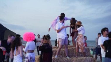 2020-07-25 - Henychensk, Ukraine. Spot Guide Kite Club - Wave Festival. Multi ethnic people in boho outfits dance enjoy open air music fest on sunset by sea. Stylish audience have fun on beach party.