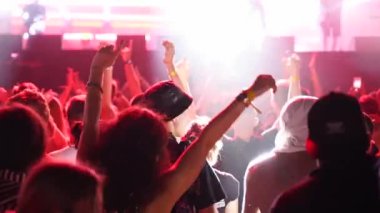 2019-08-09 - Mariupol, Ukraine. MFest festival. People dance waving hands at live music concert on open air festival. Bright colorful stage lighting. Fans at a favourite band performance.