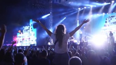 2019-08-09 - Mariupol, Ukraine. MFest festival. Woman sits on boyfriend shoulders, dance waving hands at music concert on open air fest. Crowd jump, applause, enjoy favourite band performance on stage