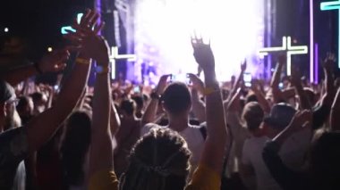 2019-08-09 - Mariupol, Ukraine. MFest festival. People silhouettes waving hands, taking photos or recording videos of live music concert with smartphones at an open air fest. Colorful stage lighting.