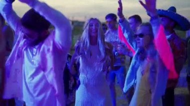 2020-07-25 - Henychensk, Ukraine. Spot Guide Kite Club - Wave Festival. Multi ethnic people in boho outfits dance enjoy open air music fest on sunset by sea. Stylish audience have fun on beach party.