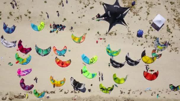202020 ウクライナのHenychensk カイトサーフィンスポットで風の強い日にビーチに駐車横たわっている明るいカラフルな凧の上からの眺め キッチンボードのための多くのパラシュートが海岸にあります 空中ビデオ — ストック動画