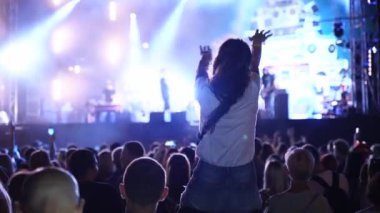 2019-08-09 - Mariupol, Ukraine. MFest festival. Woman sits on boyfriend shoulders, dance waving hands at music concert on open air fest. Crowd jump, applause, enjoy favourite band performance on stage