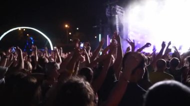 2019-08-09 - Mariupol, Ukraine. MFest festival. People silhouettes waving hands, taking photos or recording videos of live music concert with smartphones at an open air fest. Colorful stage lighting.