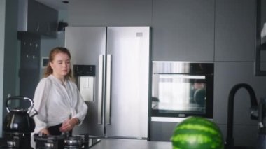 Economical inflation. Woman in kitchen looking at cash receipt and counting after shopping. Girl checks bill and calculates expenses at home after buying groceries. Female looking at phone.