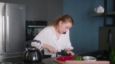 Stressed woman in hurry on multitasking rush on remote job at home. Distracted female cooking salad, answer calls, chatting with clients, works on laptop simultaneously at kitchen. Freelancer girl.
