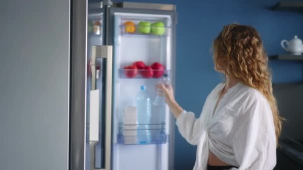 Caucasian Woman Opens Refrigerator Takes Bottle Water Drinks Cooled Water — Stockvideo